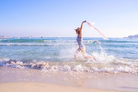 beautiful young woman in bikini runs along the sandy seashoreの写真素材