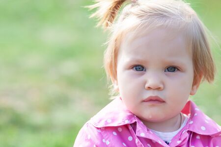 portrait of little one year old girl  in a jacket on the streetの写真素材