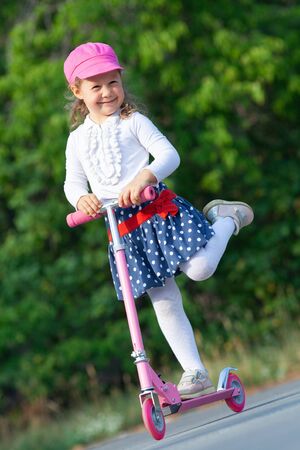 happy little girl on scooter in outdoorの写真素材