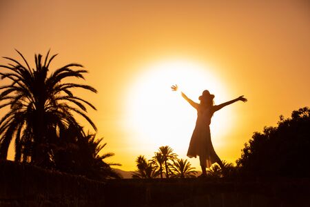silhouette of a woman enjoing  at sunset on resortの写真素材