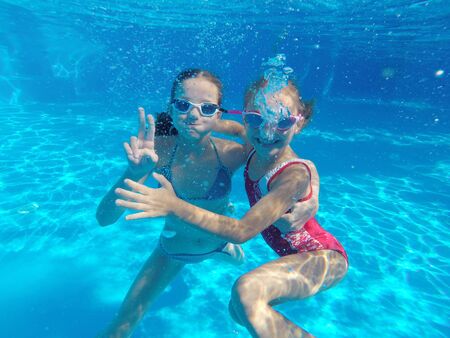 Cheerful little girls  playing under  water in pool.の写真素材