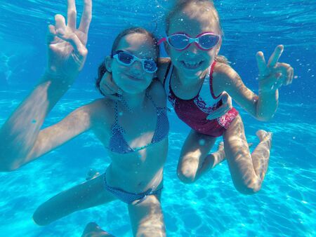 Cheerful little girls  playing under  water in pool.の写真素材