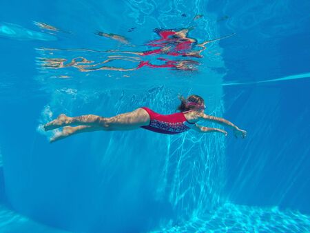 Cheerful little girl swiming under  water in pool.の写真素材