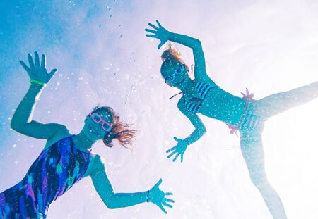 Two little girls playing under  water in pool.の写真素材
