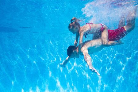 underwater photo of young dad with little girl in swimming  poolの写真素材