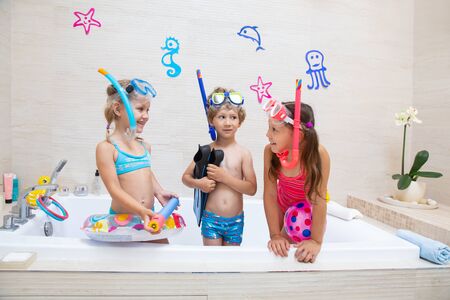funny children play in the bathroom instead of the beach on the sea because of the quarantine, due to the pandemic Covid-19の写真素材