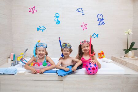 funny children play in the bathroom instead of the beach on the sea because of the quarantine, due to the pandemic Covid-19の写真素材