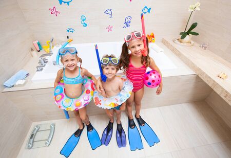 funny children play in the bathroom instead of the beach on the sea because of the quarantine, due to the pandemic Covid-19の写真素材