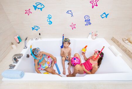 funny children play in the bathroom instead of the beach on the sea because of the quarantine, due to the pandemic Covid-19の写真素材