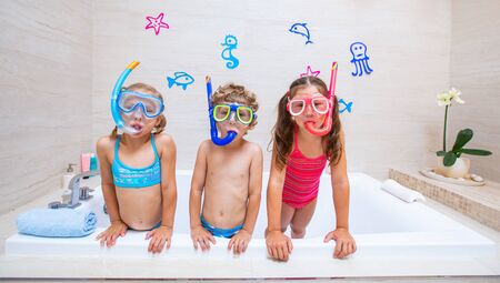 funny children play in the bathroom instead of the beach on the sea because of the quarantine, due to the pandemic Covid-19の写真素材