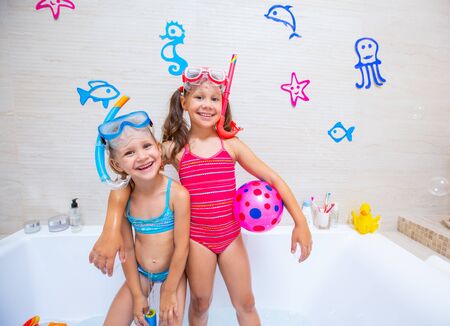 funny children play in the bathroom instead of the beach on the sea because of the quarantine, due to the pandemic Covid-19の写真素材