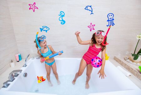 funny children play in the bathroom instead of the beach on the sea because of the quarantine, due to the pandemic Covid-19の写真素材