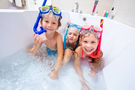 funny children play in the bathroom instead of the beach on the sea because of the quarantine, due to the pandemic Covid-19の写真素材