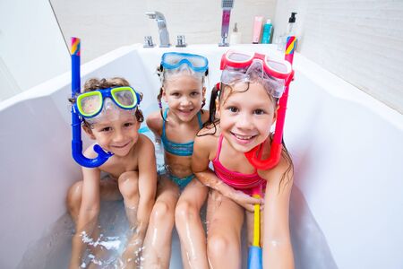 funny children play in the bathroom instead of the beach on the sea because of the quarantine, due to the pandemic Covid-19の写真素材