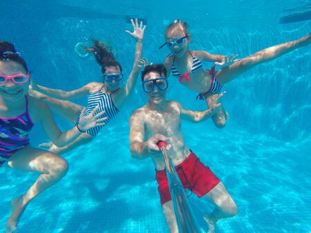 underwater photo of young family with kids in swimming  poolの写真素材