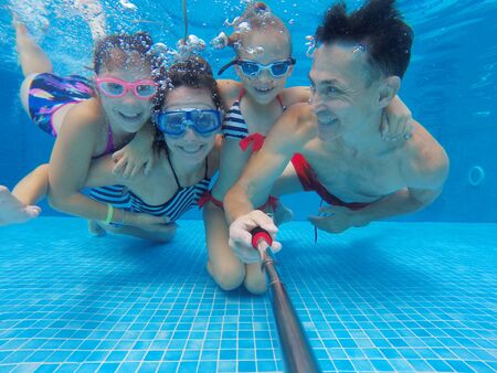 underwater photo of young family with kids in swimming  poolの写真素材