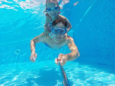underwater photo of young dad with little girl in swimming  poolの写真素材