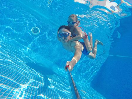 underwater photo of young dad with little girl in swimming  poolの写真素材