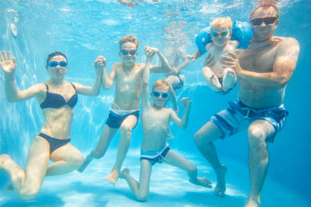 underwater photo of big young family with kids in swimming poolの写真素材