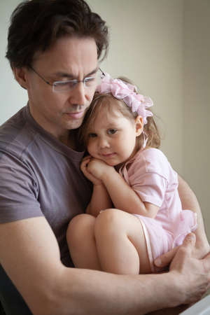 amateur portrait of a young dad with a small daughter in her arms at homeの写真素材