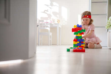 little girl plays toys in the nursery aloneの写真素材