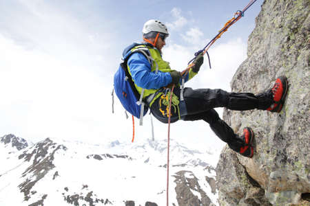 mountaineer descends from the mountain in the background of the landscape of snowy mountainsの写真素材