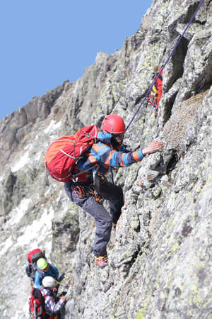 man mountaineer with ice ax climbs on the rock in mountainsの写真素材