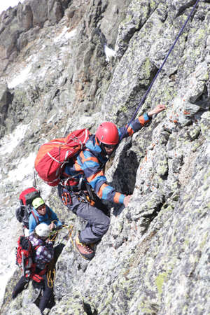 man mountaineer with ice ax climbs on the rock in mountainsの写真素材