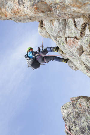 mountaineer woman descends from the mountain in the background of blue skyの写真素材