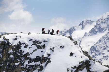 group of mountaineers with backpacks goes along the snowy slope of the mountainの写真素材