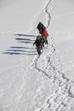 group of mountaineers with backpacks goes along the snowy slope of the mountainの写真素材