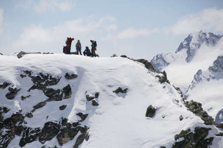 group of mountaineers with backpacks goes along the snowy slope of the mountainの写真素材