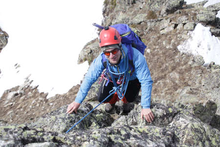 man mountaineer with ice ax climbs on the snowy mountainsの写真素材