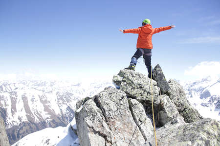 climber woman climbs into the mountains against the backdrop of the landscape of snowy mountainsの写真素材