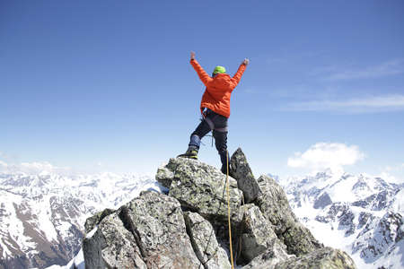 climber woman climbs into the mountains against the backdrop of the landscape of snowy mountainsの写真素材