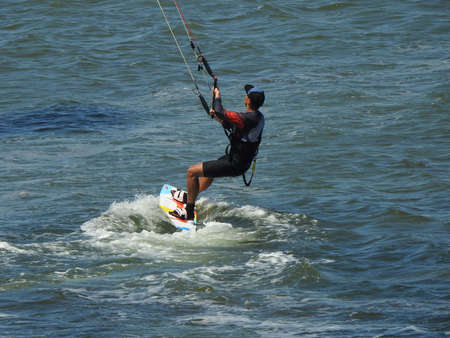 young sporty man kitesurfing on the sea off the sandy coast.の写真素材