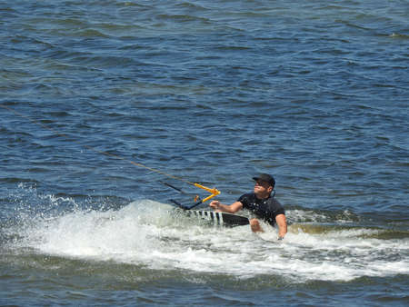 young sporty man kitesurfing on the sea off the sandy coast.の写真素材