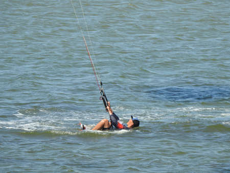 young sporty man kitesurfing on the sea off the sandy coast.の写真素材