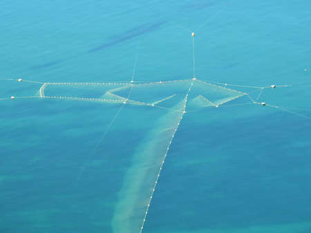 photograph of a large fishing net in the blue seaの写真素材