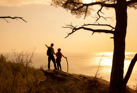 two people have hiking through seacast on sunsetの写真素材