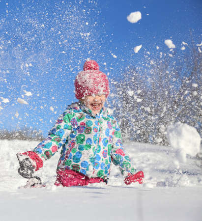 little girl playing on snow in winter timeの写真素材