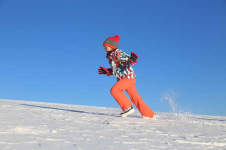 little girl runnying on snow in winter timeの写真素材