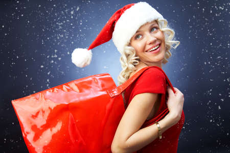 Beautiful girl dressed as santa holding a red bag for new year shoppingの写真素材