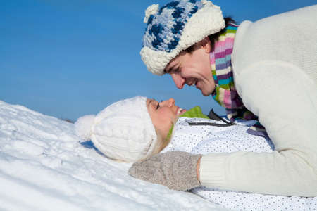young couple playing and kissing on snow hill in winterの写真素材