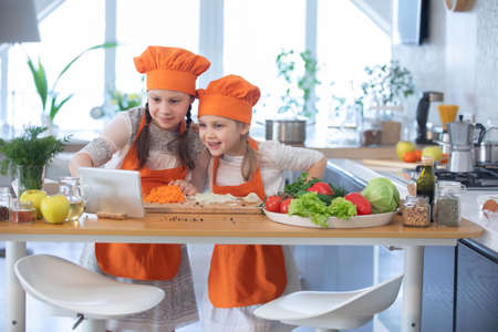 Two little girls cooking in the kitchen at homeの写真素材