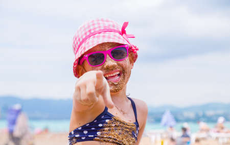 little girl lying on a sandy beach and sunbathe in the sunの写真素材