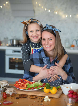 Mother with little daughter have cooking together in the kitchen at homeの写真素材