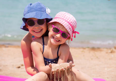 little girls playing on a sandy beach and sunbathe in the sunの写真素材