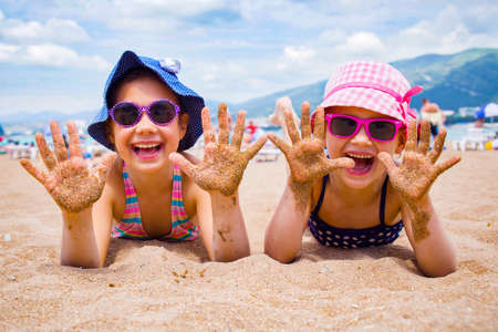 little girls playing on a sandy beach and sunbathe in the sunの写真素材