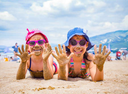 little girls playing on a sandy beach and sunbathe in the sunの写真素材